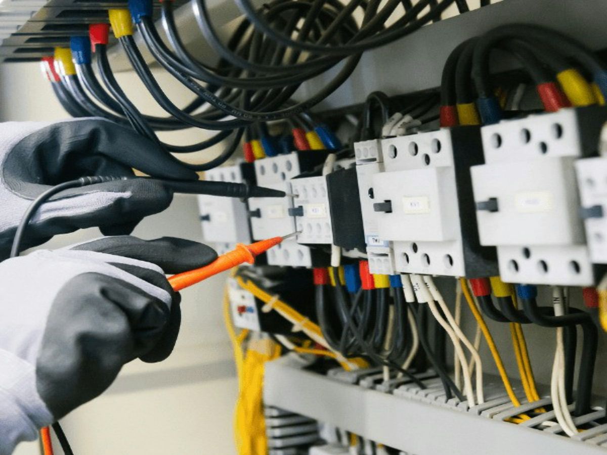 Iemand meet met een testpen aan de contactors in een schakelkast