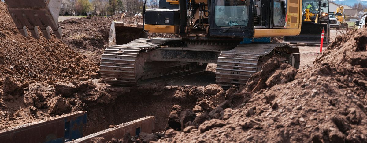 Een graafmachine maakt een sleuf in losse grond